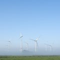 Wind turbines in green meadow near aurich in ostfriesland on misty morning in august