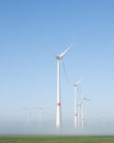 Wind turbines in green meadow near aurich in ostfriesland on misty morning in august