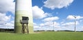 Wind turbines and high seat in german eifel in green grass with blue sky and white clouds Royalty Free Stock Photo