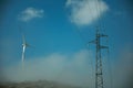 Wind turbines on hill with mist next to electric tower Royalty Free Stock Photo