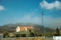 Wind turbines on hill with mist next to electric tower Royalty Free Stock Photo