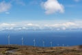 Wind turbines on the hill by the sea under a blue sky with clouds. Royalty Free Stock Photo