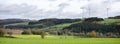 Wind turbines and mustard seed field in rural landscape of south eifel in germany