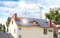 Wind turbines near house with installed solar panels. Alternative energy source Royalty Free Stock Photo