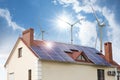 Wind turbines near house with installed solar panels. Alternative energy source Royalty Free Stock Photo