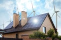 Wind turbines near house with installed solar panels. Alternative energy source Royalty Free Stock Photo