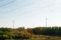 wind turbines producing electricity above forest with multiple high voltage