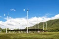 Wind turbines with solar panels farm on mountanis landscape against blue sky with clouds background Royalty Free Stock Photo