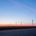 Wind turbines at sunset along highway morning commute Royalty Free Stock Photo