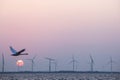 Wind turbines and swan in colorful sky with red sun