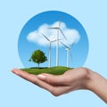 Wind turbines with tree in female hand Royalty Free Stock Photo