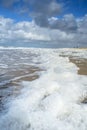 Wind and waves create foam on the beach Royalty Free Stock Photo