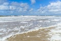 Wind and waves create foam on the beach Royalty Free Stock Photo