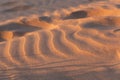 Wind waves patter on sand at sunset.