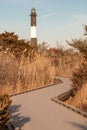 Winding boardwalk pathway leading to a large lighthouse. Fire Island New York Royalty Free Stock Photo