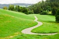 Winding country road between green fields in the mountains. Royalty Free Stock Photo