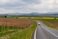 A winding country road, plowed fields, canola fields, and mountains in background Royalty Free Stock Photo