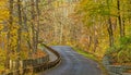 winding curving uphill country road through Fall colors forest