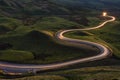Winding curvy rural road with light trail from headlights leading through British countryside. Royalty Free Stock Photo