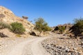 Winding gravel dirt road through rocky limestone Hajar Mountains in United Arab Emirates