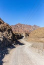 Winding gravel dirt road through rocky limestone Hajar Mountains in United Arab Emirates