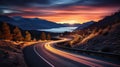 Winding lakeside road at night, bathed in the ethereal glow of moving car lights and a surreal sunset Royalty Free Stock Photo