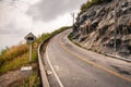 Winding mountain asphalt road with road sign to the sky. Royalty Free Stock Photo