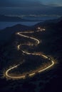 A winding mountain road at night, city lights in the distance, ocean beneath, under a dark blue sky, ai generative Royalty Free Stock Photo