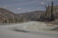 A winding mountain road. Trees on the slopes of the mountains. Blue sky. Sunny day. Royalty Free Stock Photo