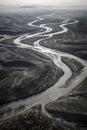 A winding river flows through rugged mountains under a hazy sky, creating a serene and majestic natural landscape