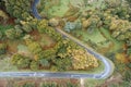 Winding road through the forest, from high mountain pass, in autumn time. Aerial view by drone Royalty Free Stock Photo