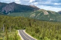 Winding road goes through a boreal forest in Denali National Park Alaska. Sunny summer day. Mountains in background Royalty Free Stock Photo