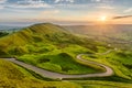 Long winding country road leading through rural countryside in the English Peak District with beautiful evening sunlight. Royalty Free Stock Photo