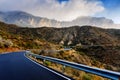 Winding road leads to high mountains with clouds to escape the routine and live adventures in nature Royalty Free Stock Photo