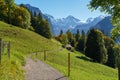 A winding road leads to a small barn on a hillside with the alps in the distance Royalty Free Stock Photo