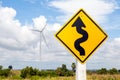 Winding road sign and windmill background in wind farm.