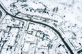 Winding road surrounded by residential houses covered by snow. aerial drone view