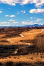 Winding road thru hills in early spring time and snow covered mountain peaks in the far background Royalty Free Stock Photo