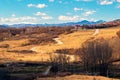 Winding road thru hills in early spring time and snow covered mountain peaks in the far background Royalty Free Stock Photo