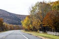Winding road in the Vermont mountains with autumn yellowed maple trees along the road and on the mountains