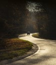 Winding rual road with car inside colorful autumn forest Royalty Free Stock Photo