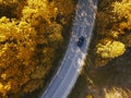 Winding rual road inside autumn forest with black car Royalty Free Stock Photo