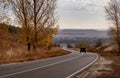 Winding rual road inside colorful autumn forest with black car