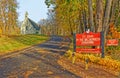 winding uphill asphalt driveway leading to historic little country church in Fall