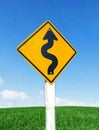 Winding yellow traffic road sign isolated on blue sky background closeup. Royalty Free Stock Photo