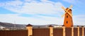 Windmill and brown fence on a blue sky background