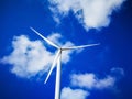 Windmill close up on blue sky and white cloud background. Wind-turbine on wind farm in rotation to generate electricity energy on Royalty Free Stock Photo