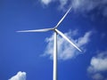 Windmill close up on blue sky and white cloud background. Wind-turbine on wind farm in rotation to generate electricity energy on Royalty Free Stock Photo