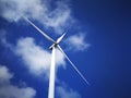Windmill close up on blue sky and white cloud background. Wind-turbine on wind farm in rotation to generate electricity energy on Royalty Free Stock Photo
