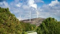 Windmill electric power turbines rotating on the high hill next to highway. Concept of green electricity, renewable power and